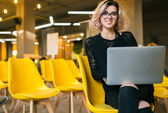 portrait-of-young-attractive-woman-sitting-in-lecture-hall-working-on-laptop-wearing-glasses-student-learning-in-classroom-with-many-yellow-chairs-110cc2622b1b62422e734991d5f72d66.png